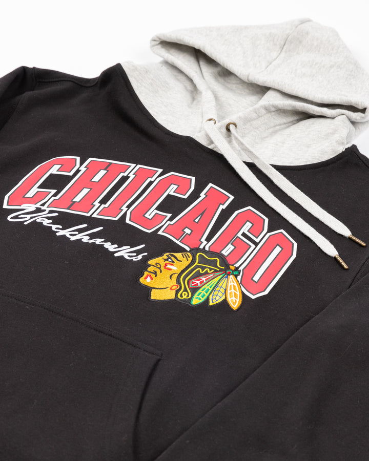 two tone black and grey Mitchell &amp; Ness hoodie with Chicago Blackhawks wordmark and primary logo on front - front detail lay flat