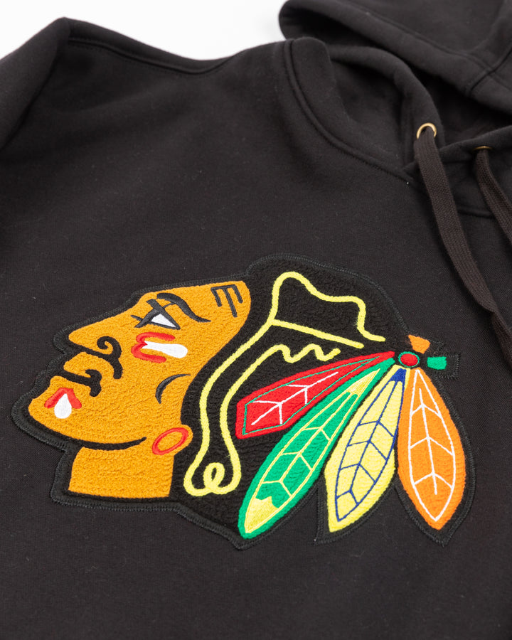 black Mitchell &amp; Ness hoodie with chainstitch Chicago Blackhawks primary logo on front and ribbed cuffs - front detail lay flat