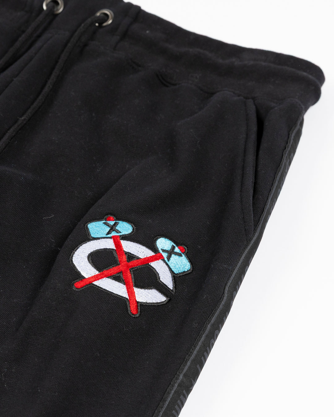 black sweatpants with Chicago Blackhawks secondary logo embroidered in Chicago flag colorway on left thigh and Chicago neighborhood names down sides - alt detail lay flat